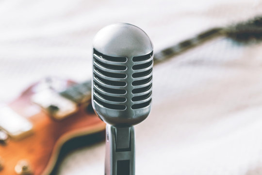 etro microphone on blurred background with electric guitar lying on white blanket