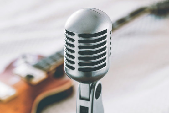etro microphone on blurred background with electric guitar lying on white blanket