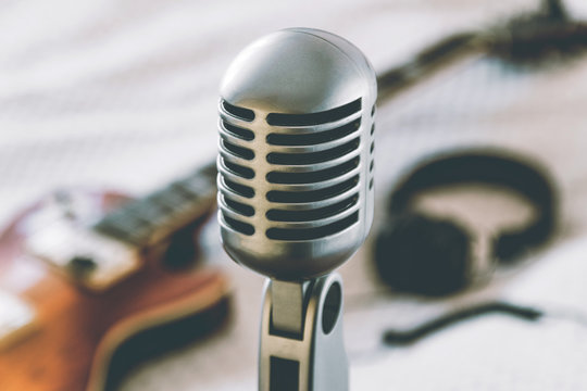 etro microphone on blurred background with electric guitar lying on white blanket