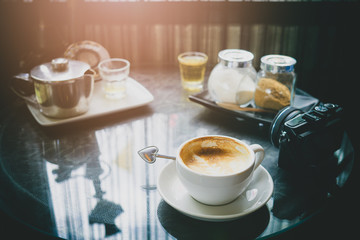 Coffee and Tea Time Relaxing time from travel concept. Cup of Coffee , tea, camera and teapot on table in a cofee shop.