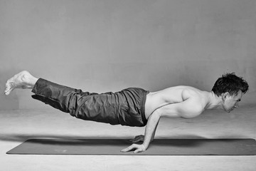 young man is engaged in yoga in a studio