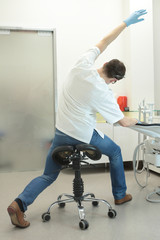 male dentist stretching his legs and arms in the office during break