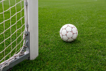 Soccer ball on the soccer field background with goal post on the right. Football ball on the...