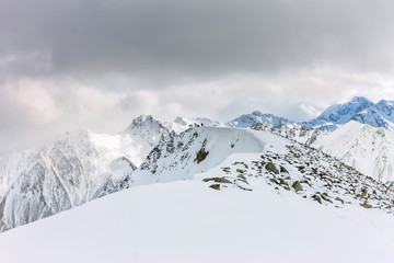 Snowy mountains aero photo drone, clouds approaching peaks and valley