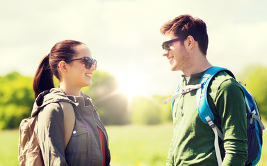 Fototapeta premium travel, hiking, backpacking, tourism and people concept - happy couple with backpacks talking outdoors
