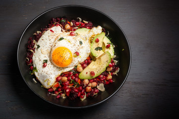 Miso veggie breakfast bowl with beets, carrots, brussels sprouts, kale, chickpeas, and topped with pomegranate seeds, avocado and fried egg.