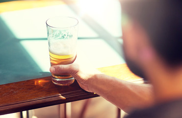 people, drinks, alcohol and leisure concept - close up of man drinking beer from glass at bar or pub