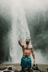Obraz premium Young handsome tourist visiting the nungnung waterfall in the bali island, indonesia. Having fun in the wild nature. Lifestyle. Travel photography.