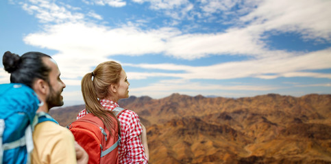 travel, tourism, hike and adventure concept - couple of travelers with backpacks over grand canyon national park hills background