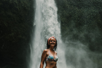 Fototapeta na wymiar Young beautiful tourist visiting the nungnung waterfall in the bali island, indonesia. Having fun in the wild nature. Lifestyle. Travel photography.