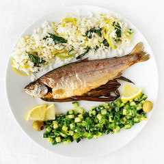 roasted trout with leek spinach rice and cucumber salad with onion decorated with lemon and olives