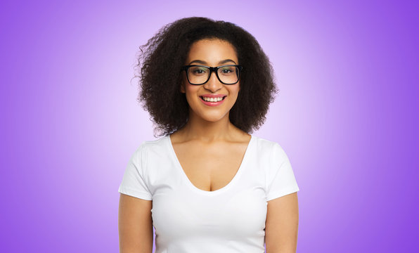 vision, body positive and people concept - happy smiling african american woman in white t-shirt and glasses over ultra violet background