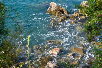 Huge stones in the sea and waves. On a sunny day. View from above. Montenegro. The Budva Riviera