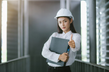 A young lady engineer thumbs up and looks at the camera.