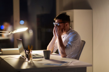business, overwork, deadline and people concept - tired businessman with laptop computer working at night office