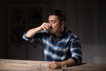Fototapeta premium alcoholism, alcohol addiction and people concept - male alcoholic drinking shot at night