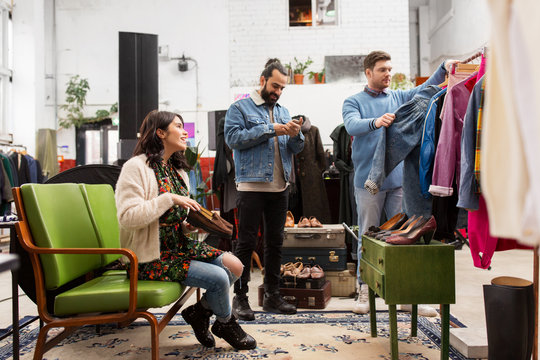 sale, shopping, fashion and people concept - friends choosing clothes and footwear at vintage clothing store
