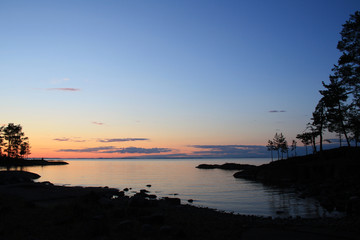 Obraz premium Beautiful northern landscape. Russian North. Ladoga lake at sunset. Wild nature. Trees reflected in the water. Aged photo in retro style. Summertime. Twilight. Island of Valaam, Karelia, Russia.