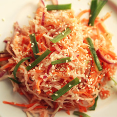 Vegan salad with carrot and radish. Top view. Asian cuisine. Healthy vegan appetizer on the round plate. Side dish. Vegetarian dish. Toned square photo.