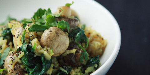 Vegetarian turmeric rice in the white bowl. Vegan dish. European cuisine. Yellow rice with mushrooms and spinach. Meatless. Wide photo.