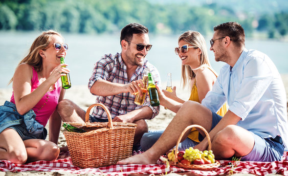 Group of friends enjoying picnic on the beach. Lifestyle, vacation, relationships concept