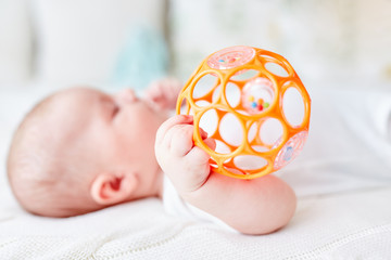 Baby greift mit einer Hand die Rassel