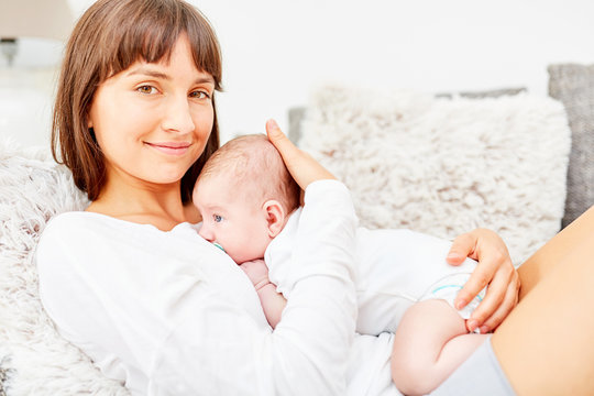 Glückliche Mutter mit Baby im Arm auf Sofa