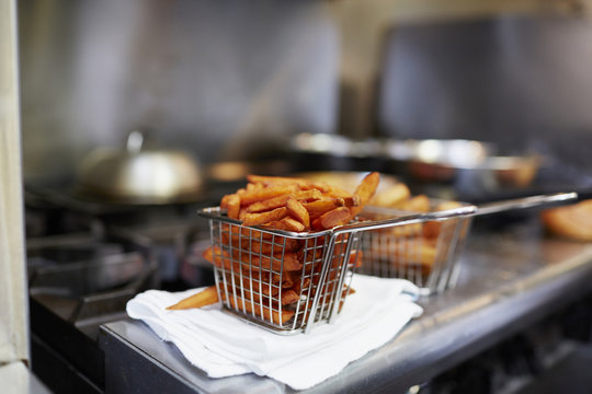 Close-up of French fries in fryer basket on kitchen counter