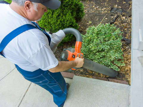 Garden worker vacuuming up dead leaves
