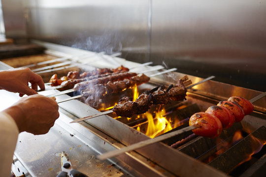 Cropped hands of chef making kebab on barbecue grill in commercial kitchen