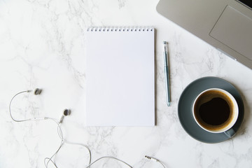 Workplace flatlay with notebook, laptop and coffee cup on marble table