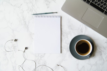 Workplace flatlay with notebook, laptop and coffee cup on marble table