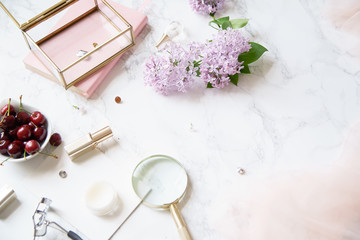 Top vew composition with feminine workspace mock up with lilac flowers and pink accessories on marble background