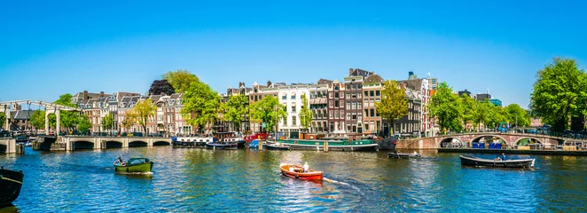 Foto op Plexiglas Amsterdam Amsterdam, 7 mei 2018 - uitzicht op de rivier de Amstel gevuld met kleine boten en de Magere brug (magere brug) op de achtergrond op een zomerdag
