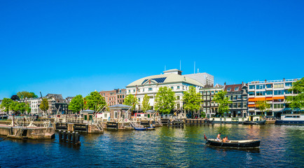 Fototapeta na wymiar Amsterdam, May 7 2018 - view on the river Amstel filled with small boats and the Carre theater in the background on a summer day