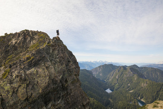 Mid distance view of hiker standing on cliff against sky