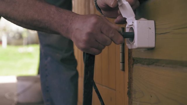 A carpenter is plugging in a power cord of grinder. Man is using an electric saw closeup view. Slow motion.