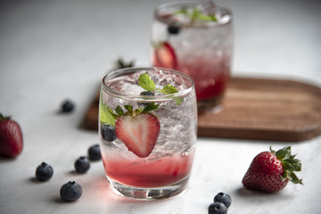 Red and clear cocktail on WoodenTray and strawberry and blueberry.