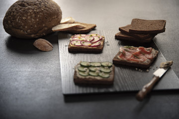 Bread made with salmon, cucumber, honey and knife placed on a wooden tray.