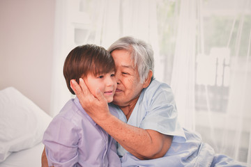 Obraz premium Patient Concept. Grandma's in the hospital. Waiting for someone to visit. Grandchildren visit grandma at the hospital. Grandma is happy to meet grandchildren.