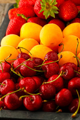 Fresh ripe summer berries and fruits (apricots, cherry and strawberry) 