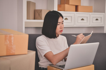 Sme business concept. Young Asian people are packing their packages.Delivery business  Small and Medium Enterprise (SMEs). Young man is working in the house.Young Owner Start up for Business Online.