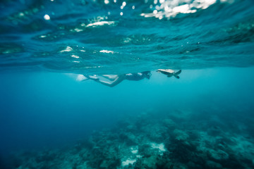 Fototapeta na wymiar Snorkeling girl swimming with sea turtle