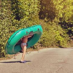Portrait of young boy carrying a rubber boat to the river, image with square aspect ratio and warm toning