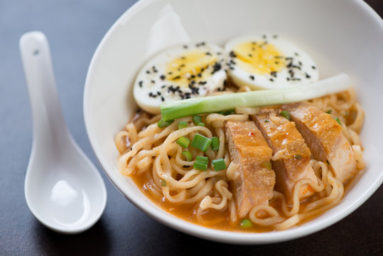 Close-up of ramen noodles with roasted chicken, egg, green onion and sesame seeds, selective focus