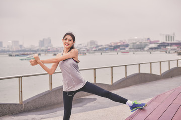 Sports concept. Beautiful girl is exercising on the beach with warm up. Beautiful girl is happy to...