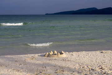 Fototapeta na wymiar Sand castle on beach in sunset light. Tropical seaside landscape with white sand beach.
