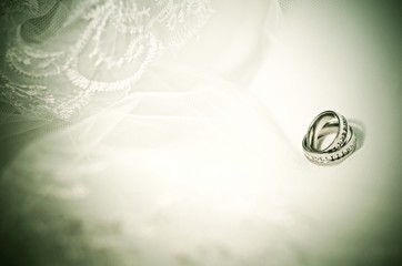 Two wedding rings on a wedding veil background