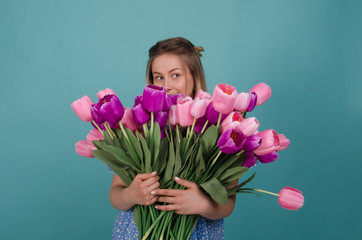 Cute woman with flowers. Pretty young woman with bunch of flowers in her hands  isolated on blue background. Spring and summer holidays. Women's Day. Beauty, fashion concept.