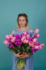 Woman with tulips.  Cute woman with bouquet. Young female with pink and purple flowers natural portrait lifestyle.Summer and spring concept. Isolated on blue studio background